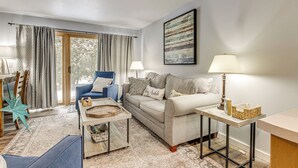 Un salon avec un canapé, des fauteuils, une table basse et une lampe.