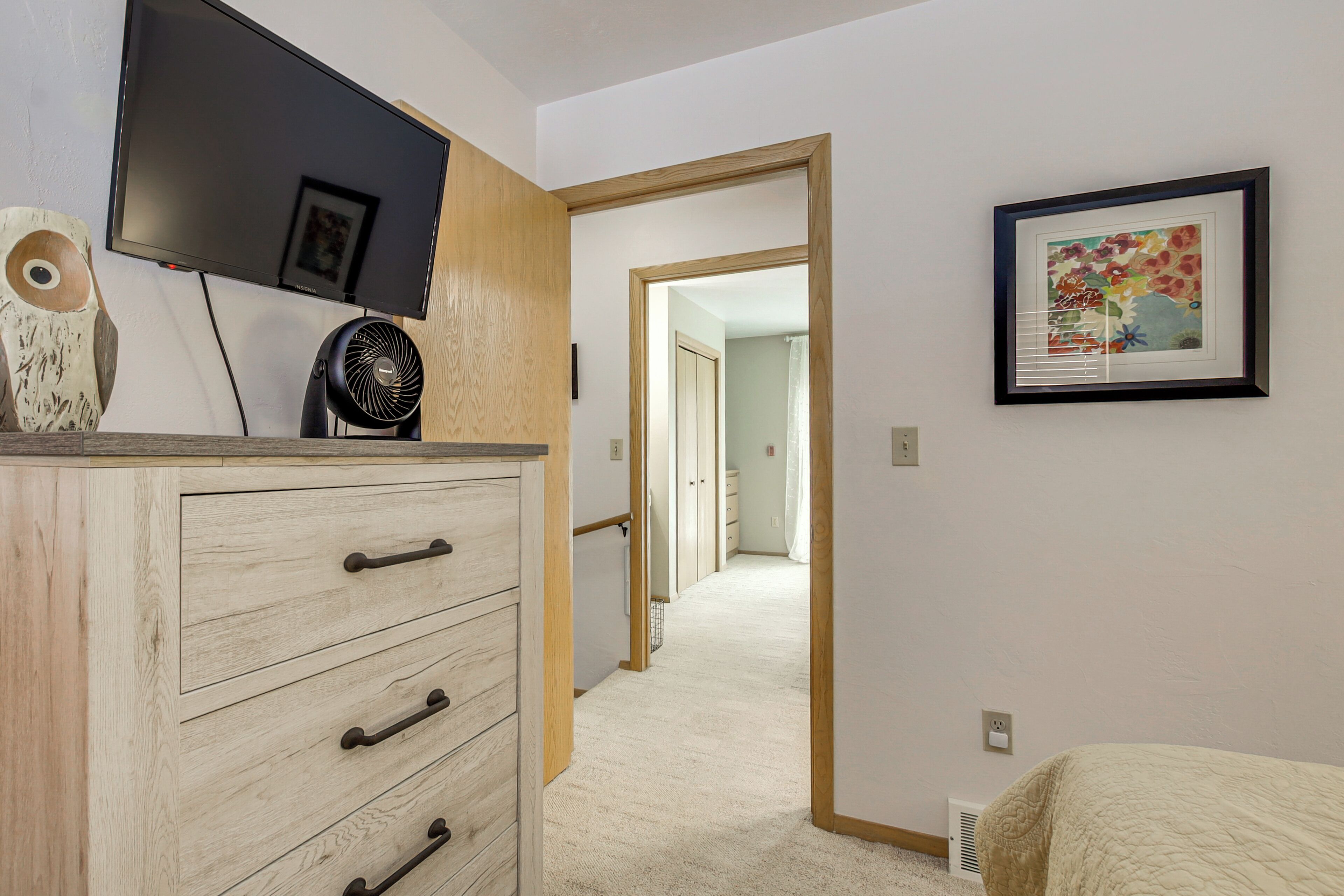 A bedroom with a bed, a dresser, a TV, and a framed picture on the wall.