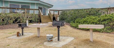 A beachfront house with a wooden deck, a staircase leading to the entrance, and a mailbox.
