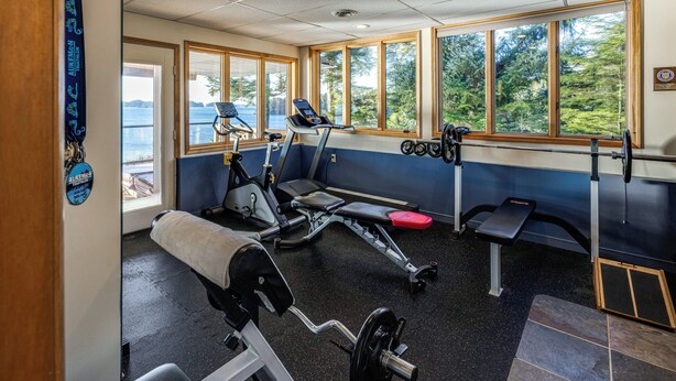 Une salle de sport équipée de tapis de course, d’appareils de musculation et d’un banc.