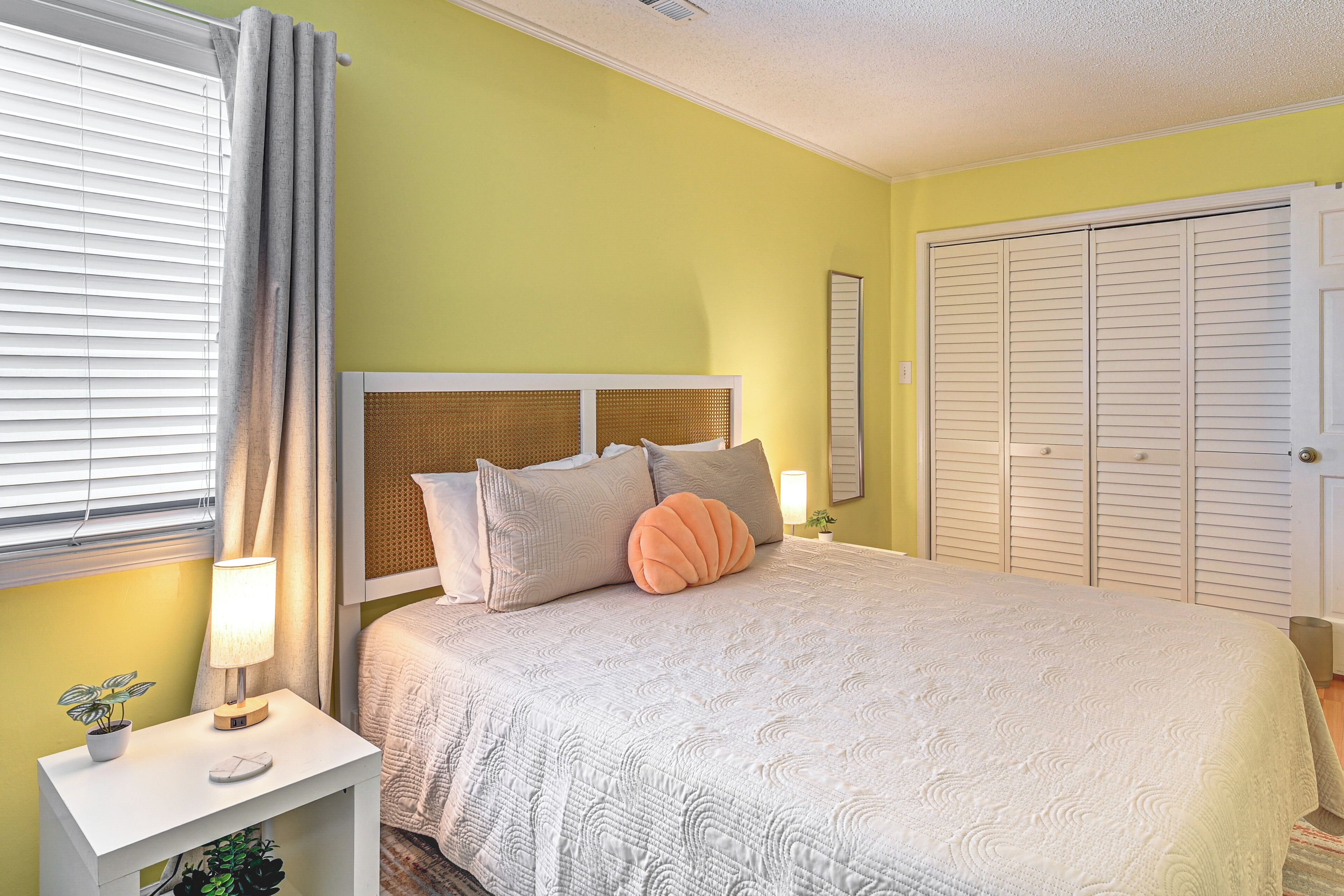 A bedroom with a bed, bedside table, lamp, and a closet.