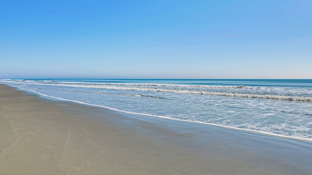 Una spiaggia con cielo sereno e mare calmo.
