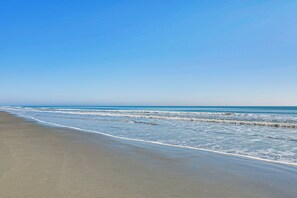 Uma praia com céu claro e mar calmo.