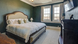 Un dormitorio con una cama grande, ventilador de techo, cómoda y ventana con cortinas.