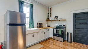 Una cocina moderna con armarios blancos, un refrigerador de acero inoxidable, una encimera de madera y un horno negro.