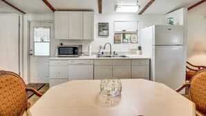 A kitchen with white cabinets, a microwave, a sink, and a refrigerator. - Cabin w/ Lake Access in Fort Mccoy, Pets Welcome! (Fort McCoy)