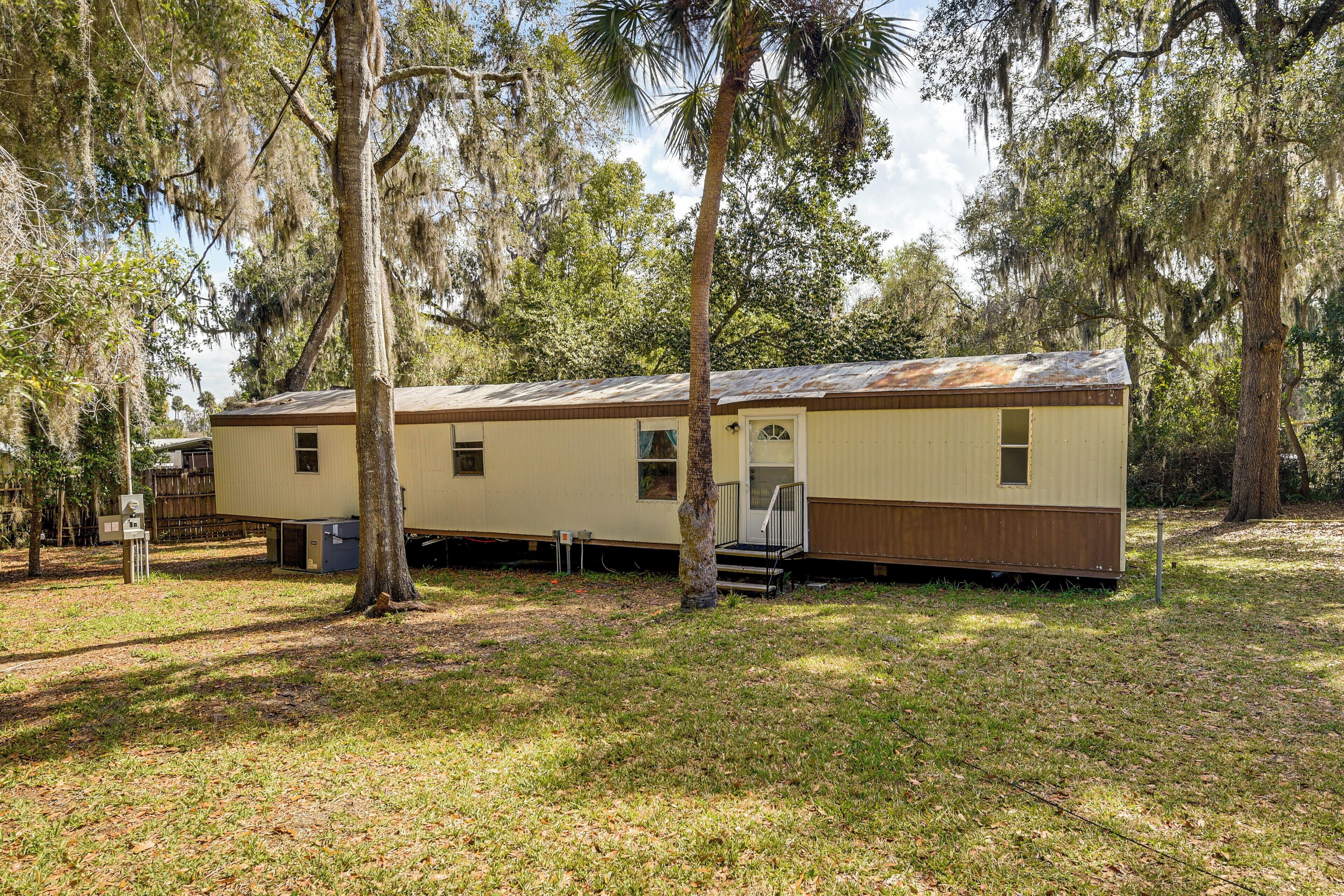 A mobile home with a single entry door, a small porch, and a fenced yard.