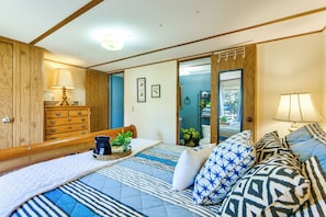 A bedroom with a bed, wooden dresser, and a mirror.