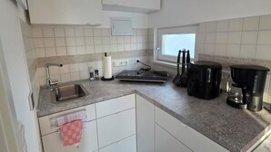 Een koffiezetapparaat/waterkoker, een koelkast, een oven, een kookplaat
