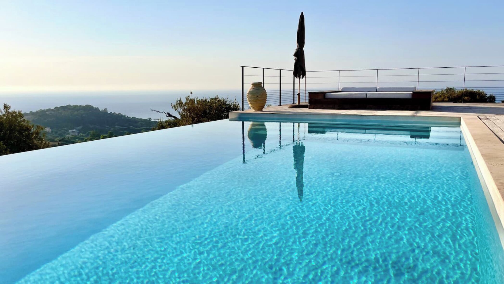 Une magnifique piscine à débordement avec vue sur la mer et les collines.
