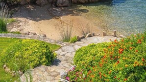 En trädgård vid kusten med fri utsikt över havet, en gång av sten och olika sorters blommande växter.
