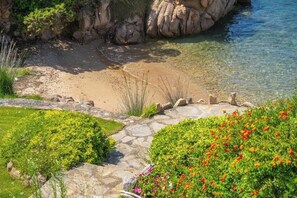 Ein Küstengarten mit freiem Blick auf das Meer, einem Kiesweg und verschiedenen blühenden Pflanzen.