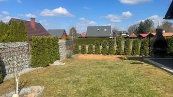 Una zona residencial con un muro de piedra, césped y una fila de árboles de hoja perenne.