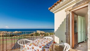A balcony with a table and chairs, overlooking a coastal view. - Apartment With sea View and Great Roof Terrace (Santa Teresa di Gallura)