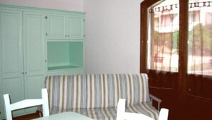 A room with a striped sofa, a white table, and a green cabinet. - Apartment With sea View and Great Roof Terrace (Santa Teresa di Gallura)