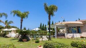 A house with a patio, palm trees, and a garden. - Studio for Couples in Capo Vaticano With Pool (Ricadi)