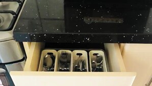 Una cucina con un piano di lavoro nero, un fornello e un cassetto con posate.
