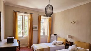 A hotel room with two beds, a desk, a radiator, and a window with curtains. - Family home, sleeps 8, terrace with panoramic view in Porquerolles (Hyères)