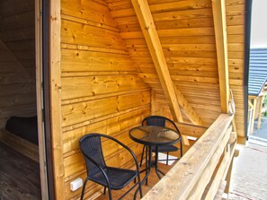 A wooden cabin with a sloped ceiling, a small round table, two chairs, and a wooden bench. - Holiday Home With a Terrace, Close to the Lake (Lubrza)