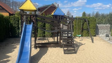 A playground with a slide, climbing structures, and a swing set.