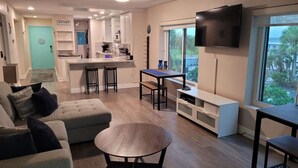 A modern living room with a sofa, a coffee table, and a TV mounted on the wall. - Waterfront Balcony Condo Beach Access Hot Tub (Ruskin)