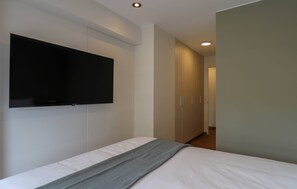 Ein Schlafzimmer mit einem Bett, einem an der Wand montierten Flachbildfernseher und einem Kleiderschrank.