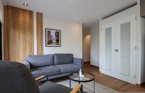Ein modernes Wohnzimmer mit einem grauen Sofa, einem kleinen runden Tisch und einer Wand mit Holzverkleidung.