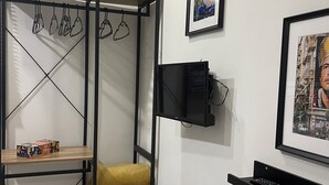 Une pièce compacte dotée d’une armoire intégrée, d’un petit coin salon et d’étagères murales.