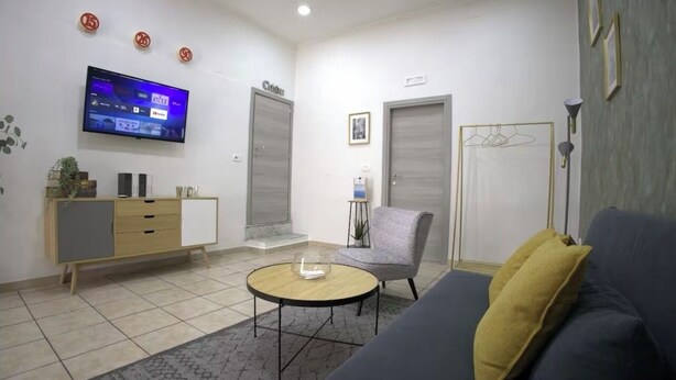 Un salon moderne comprenant un canapé, une table basse, un téléviseur fixé au mur et un meuble.