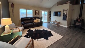 A spacious living room with a ceiling fan, a leather sofa, a coffee table, and a large rug with a cowhide centerpiece.