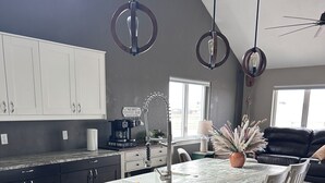 A modern kitchen with a central island, white cabinetry, and pendant lighting.