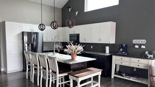 A modern kitchen with white cabinetry, a central island, and a coffee bar.