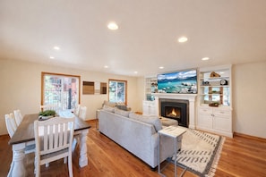 A modern living room with a fireplace, a dining area with a wooden table and white chairs, and a large TV mounted above the fireplace. - NEW property Private Skyland Beach,Modern Zephyr Cove Retreat,Hot Tub(ZC1034) (Zephyr Cove)