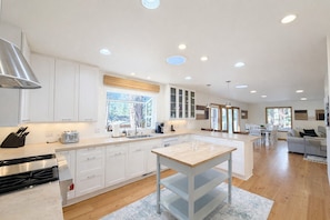 A modern kitchen with white cabinets, a central island, and a dining area with a sofa and chairs. - NEW property Private Skyland Beach,Modern Zephyr Cove Retreat,Hot Tub(ZC1034) (Zephyr Cove)