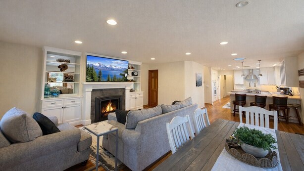 A spacious living room with a fireplace, a television mounted above it, and a dining area with a kitchen in the background. - NEW property Private Skyland Beach,Modern Zephyr Cove Retreat,Hot Tub(ZC1034) (Zephyr Cove)