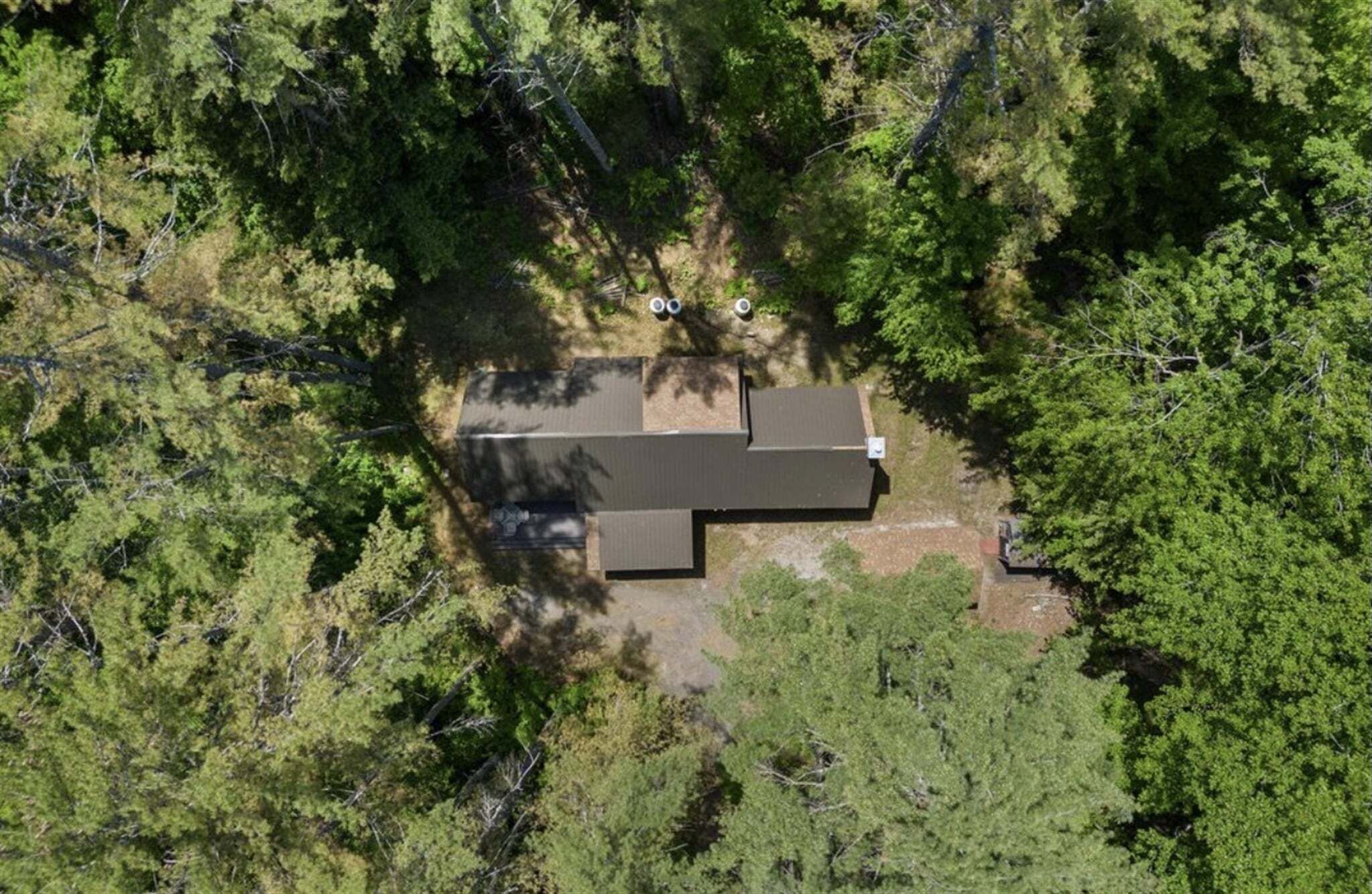 An aerial view of a single-story building surrounded by dense forest.