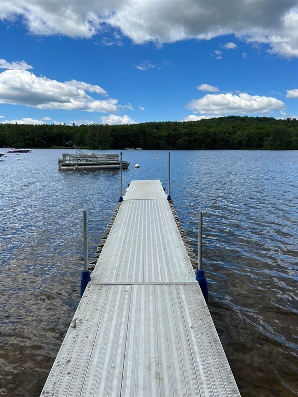 A wooden pier extending into a lake with boats docked at the end.