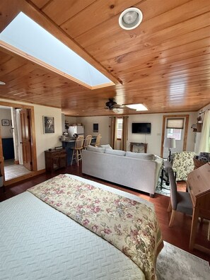 Quarto com cama, sofá, mesa de jantar e ventilador de teto.