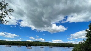 A lakeside view with boats, grassy shore, and a forested background. - Wildflower Cabins Limit 6 3 Bedroom Villa (Naples)