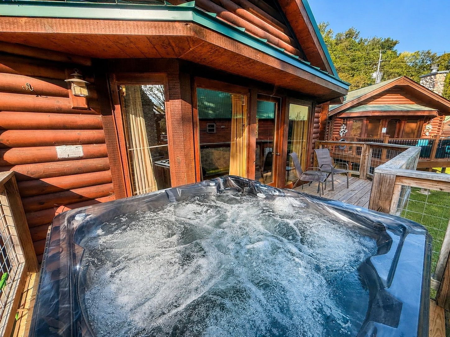 A log cabin with a hot tub in the foreground.