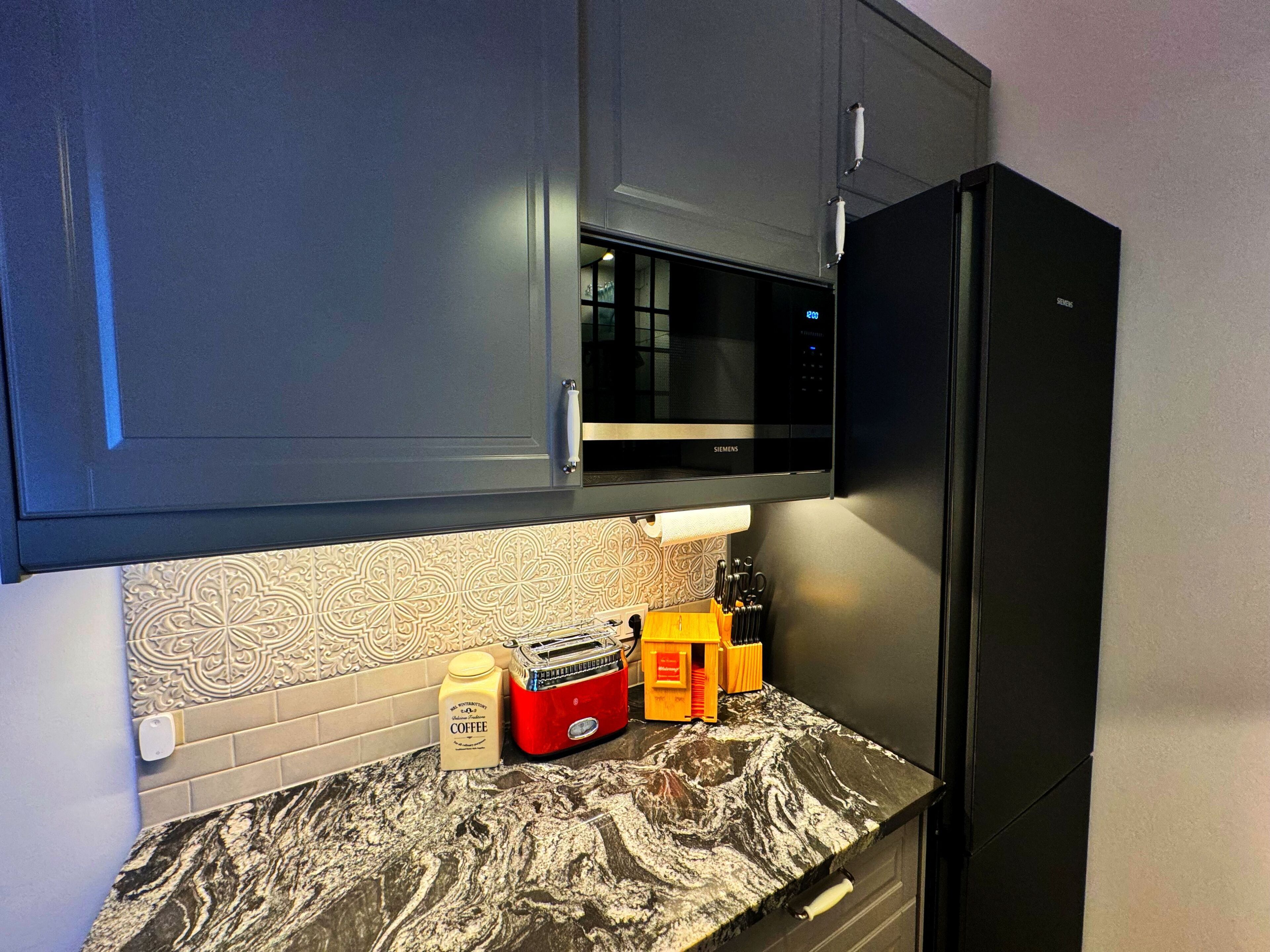 A kitchen with a black refrigerator, a microwave, and a coffee maker on the counter.