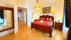 Quarto espaçoso com uma cama grande, teto ornamentado e um lustre.