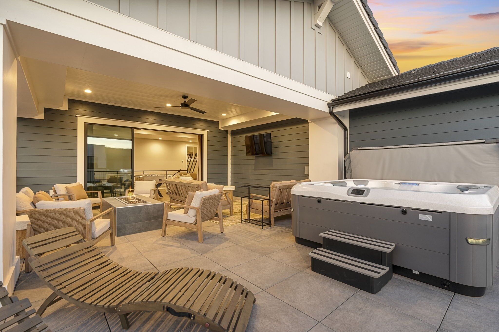 An outdoor patio with seating, a hot tub, and a covered area.
