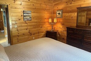 Une cabine comprenant un lit, une commode, une lampe et un panneau affichant le règlement de la cabine sur le mur.