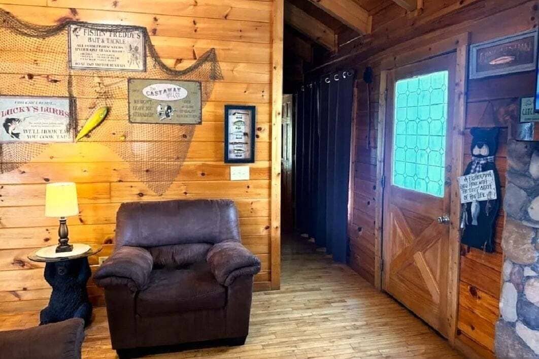 A wooden interior with a leather chair, a lamp, and various framed signs on the wall.