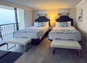 A hotel room with two beds, a bench, a nightstand, and a view of the sea. - Two Pina Coladas At San Luis Resort 2 Bedroom Condo (Galveston)