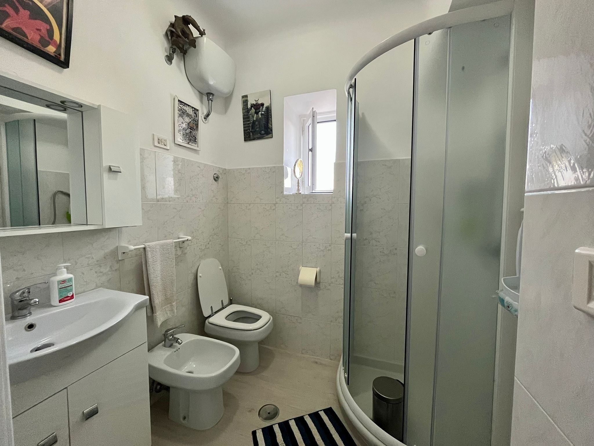 A bathroom with a sink, bidet, toilet, and a glass-enclosed shower.