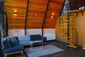 Une pièce de style loft avec un plafond en pente, un canapé bleu, un radiateur blanc et un escalier en colimaçon.