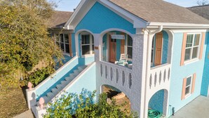 Una casa de dos pisos con fachada azul, un porche delantero y una escalera que sube al segundo piso.