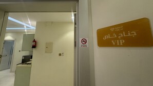 Entrada de hotel con un letrero de VIP, un letrero de prohibido fumar y un extintor en la pared.